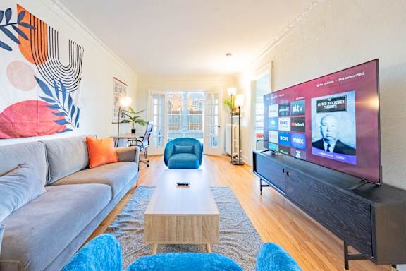 A modern living room with a grey couch, a wooden coffee table, and a large flat screen TV.