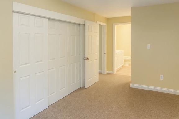 A hallway with a white door on the left and a carpeted floor.