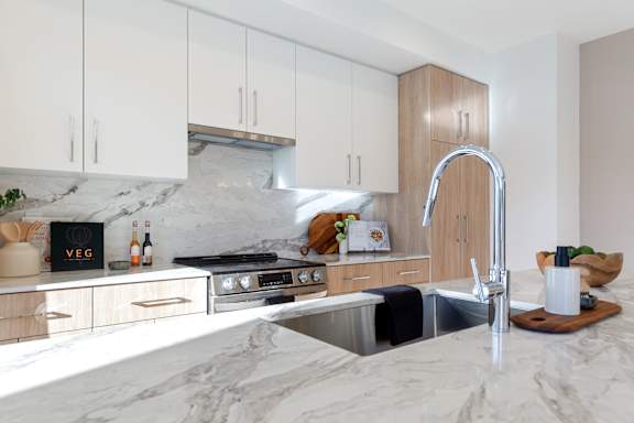 A modern kitchen with a marble countertop and a stainless steel sink.