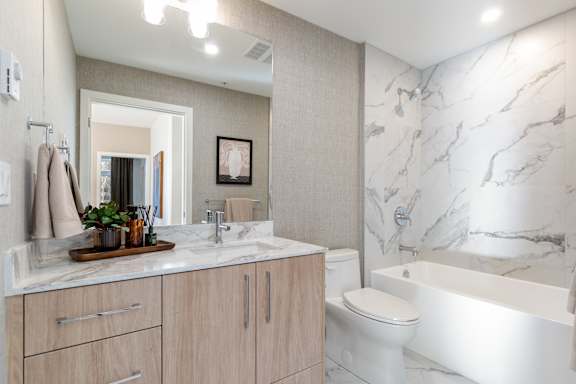 A bathroom with a marble wall and a white bathtub.