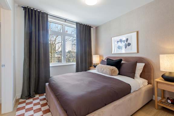 A bedroom with a large bed and a window with curtains.