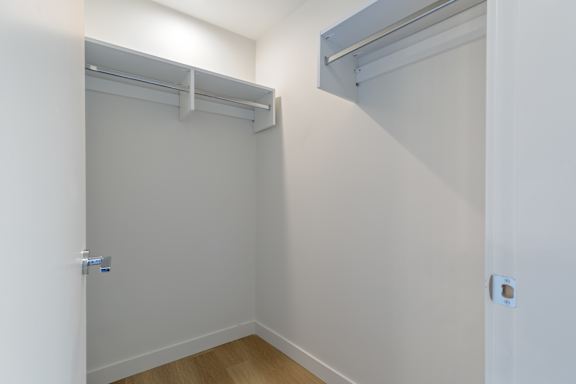 A white closet with a sliding door and a shelf above it.