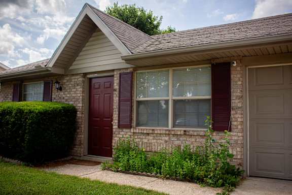 A house with a red door and a grey garage door.