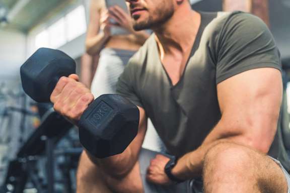 A man in a gym is lifting a dumbbell.