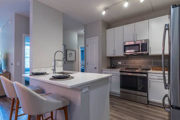 A kitchen with white cabinets and a white island.