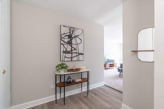 A modern living room with a large abstract painting on the wall and a small table with a plant and candles.