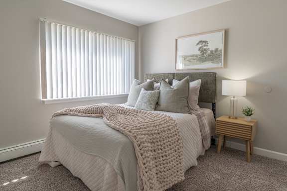 A bedroom with a large bed covered in a white blanket and pillows.