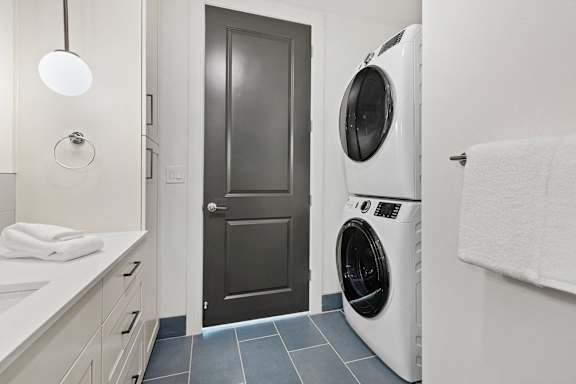 A white washing machine sits next to a door in a bathroom.