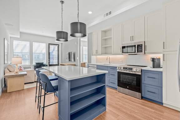 A modern kitchen with a blue island and stainless steel appliances.