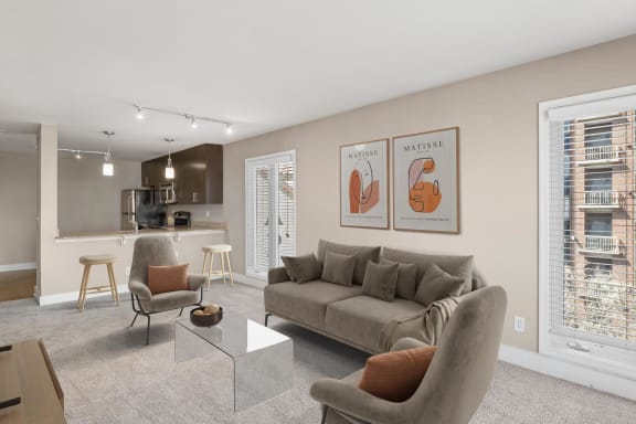 a living room with a couch coffee table and chairs and a kitchen in the background