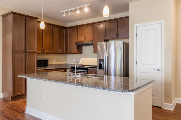 a kitchen with a granite counter top and a stainless steel refrigerator at The Residences at Bluhawk Apartment Homes, Overland Park, Kansas
