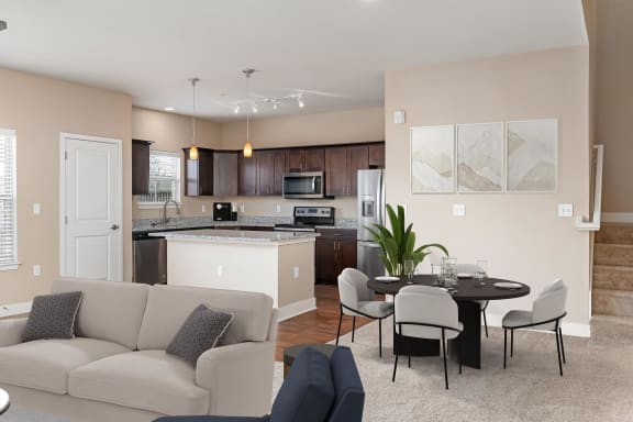 a living room with a couch a table and chairs and a kitchen with an island
