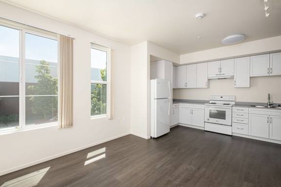 A kitchen with white appliances and wooden floors.