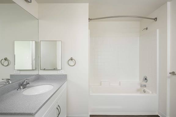 A white bathroom with a sink and a shower.