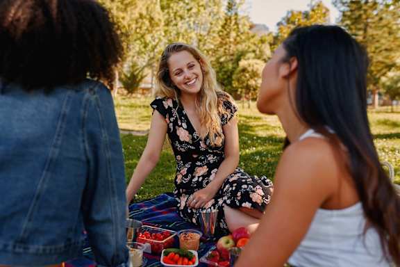 Three women having a picnic in a park.