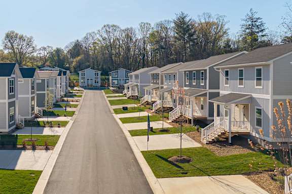 A long road in a residential neighborhood with houses on both sides.