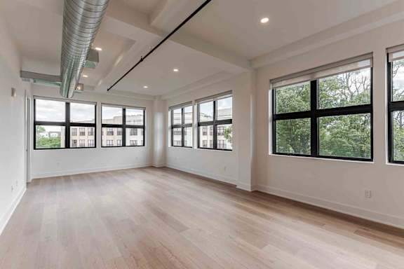 A modern, spacious living room with a large window and a comfortable couch.