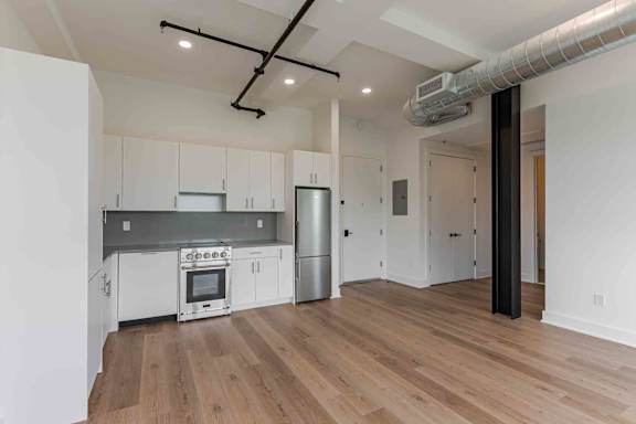 A bedroom with a large bed and a wardrobe with clothes hanging on it.