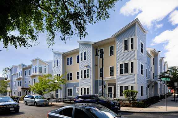 a row of apartment buildings on a city street at The Anne M. Lynch Homes at Old Colony, South Boston, MA, 02127