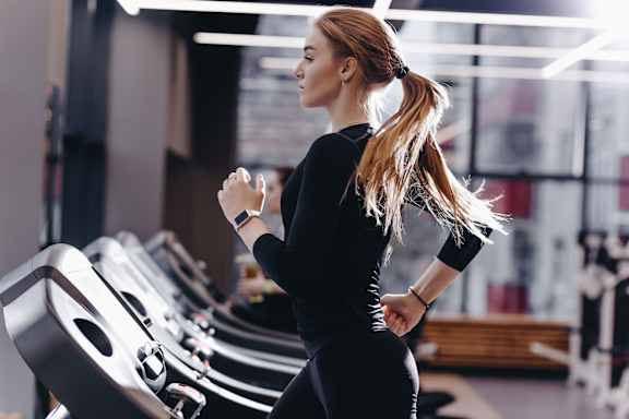 A woman in a black top and leggings is running on a treadmill in a gym.at Parkview Apartments, Memphis, TN