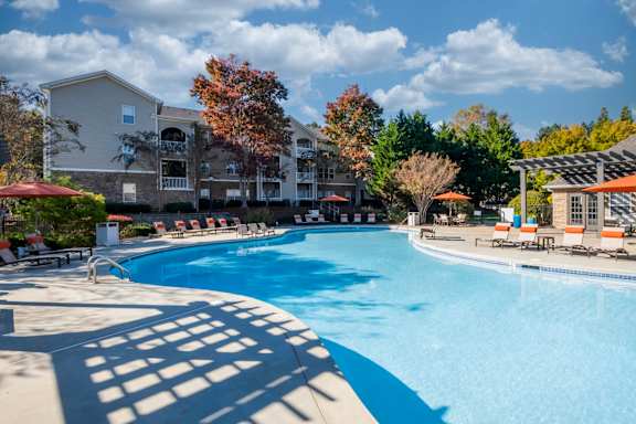 A large swimming pool surrounded by trees and apartment buildings.