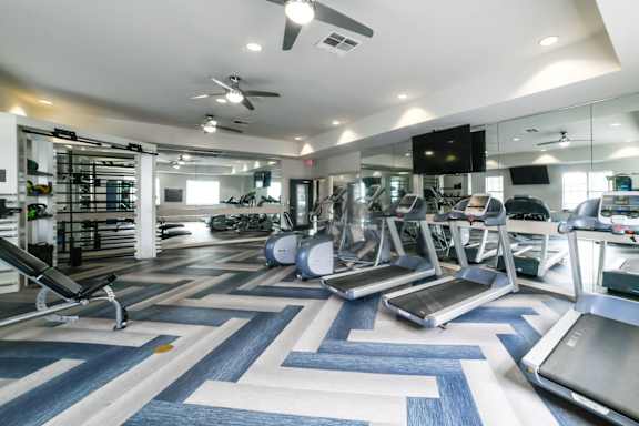 A gym with treadmills, elliptical machines, and other exercise equipment. at Sandstone Creek, Overland Park, KS, 66223