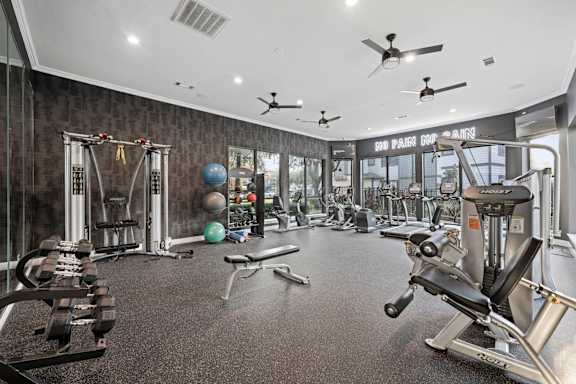 A gym with a variety of equipment including weights and cardio machines at The Ambrose, Houston, 77040