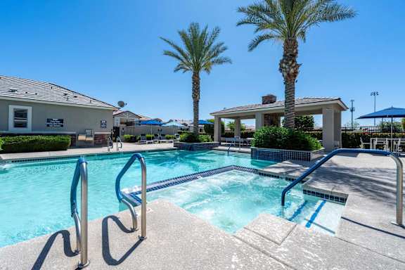 A pool with a diving board and palm trees in the background. at Vistoria At Marley Park Apartments, Arizona