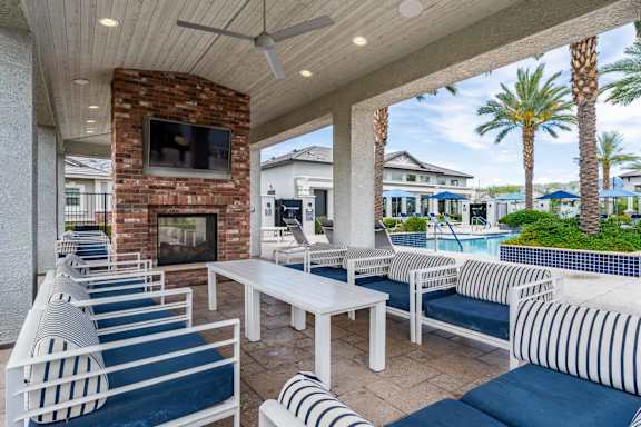 A patio with white furniture and a brick fireplace.