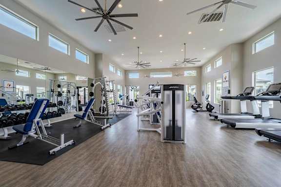 A spacious gym with a variety of equipment and a ceiling fan.