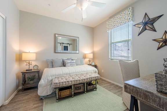 A bedroom with a bed, nightstands, and a ceiling fan.