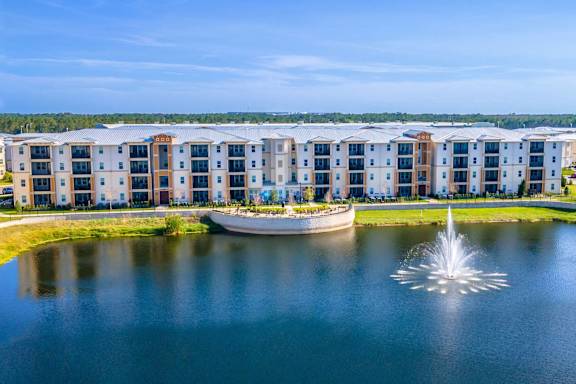 a fountain in the middle of a lake with an apartment building in the background