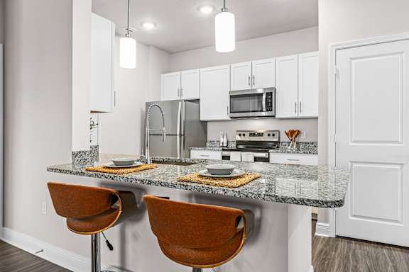 A kitchen with granite countertops and white cabinets.