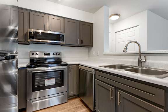A modern kitchen with a stainless steel refrigerator and grey cabinets.