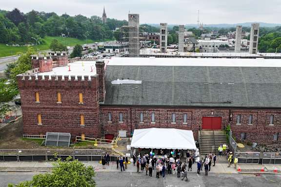 A large group of people are gathered in front of a building with a red door.
