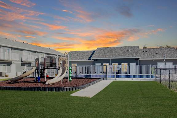 A playground with a slide and a building in the background.