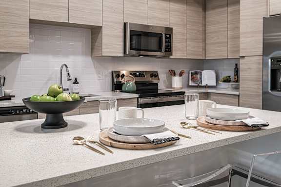 A modern kitchen with a bowl of green apples on the counter.