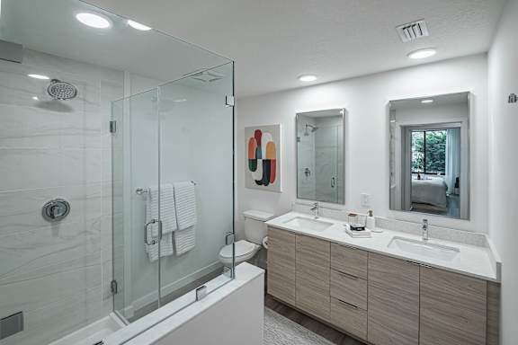A modern bathroom with a walk-in shower and double sinks.