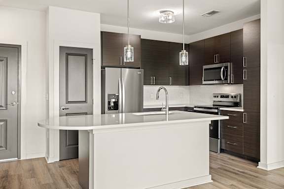 a kitchen with a large island and a stainless steel refrigerator