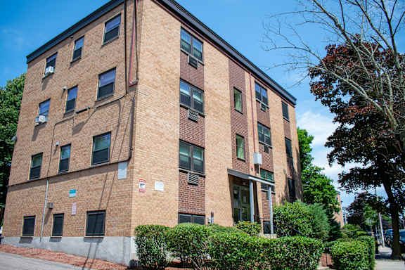 a large brick building with bushes in front of it