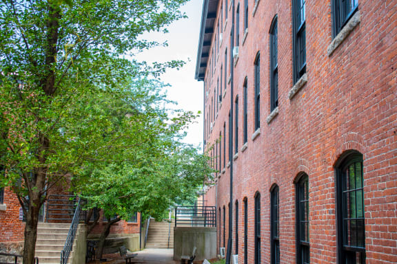a courtyard in front of a red brick building with green trees