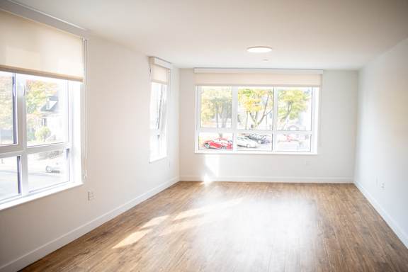 an empty living room with wood floors and large windows
