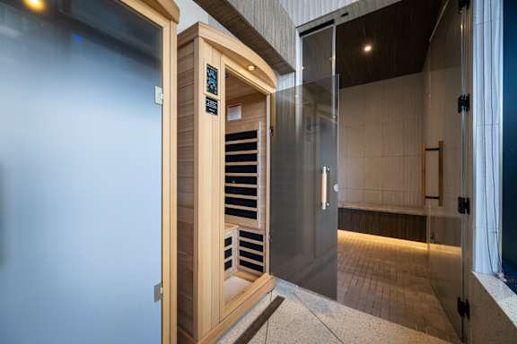 A modern bathroom with a glass door and a wooden cabinet.