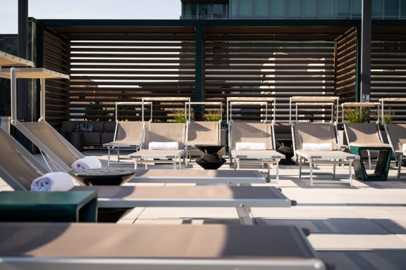 a row of lounge chairs on a patio with a building in the background