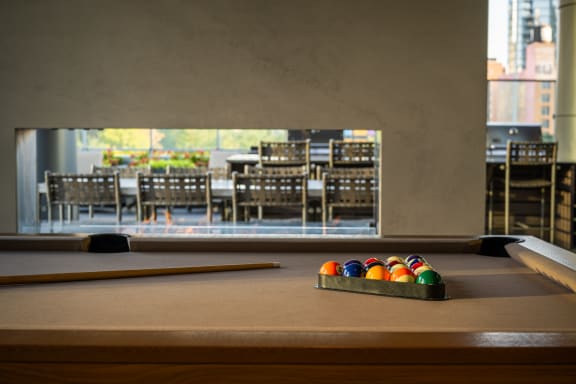 a pool table with a view of a dining room in the background