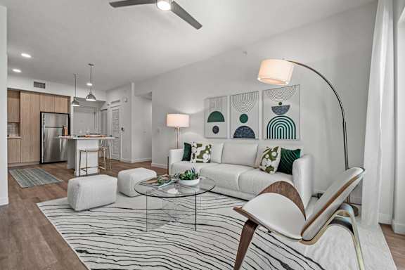 A modern living room with a white sofa, a glass coffee table, and a striped rug