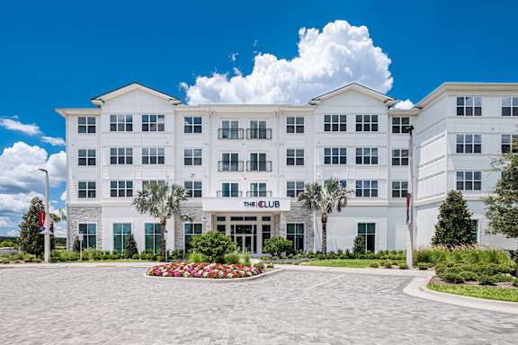 A large white building with a glass entrance and two palm trees in front at Altis Grand Twin Lakes, Kissimmee, 34744