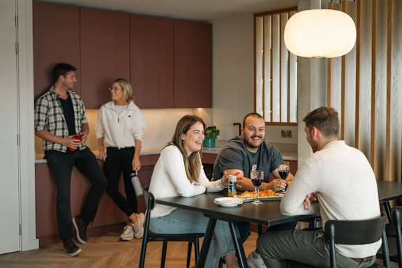 A group of people are gathered around a table eating and drinking.