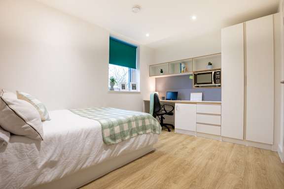 A bedroom with a bed, desk, and chair.