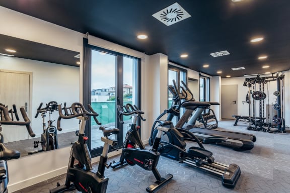 a gym with treadmills and other exercise equipment in a room with windows